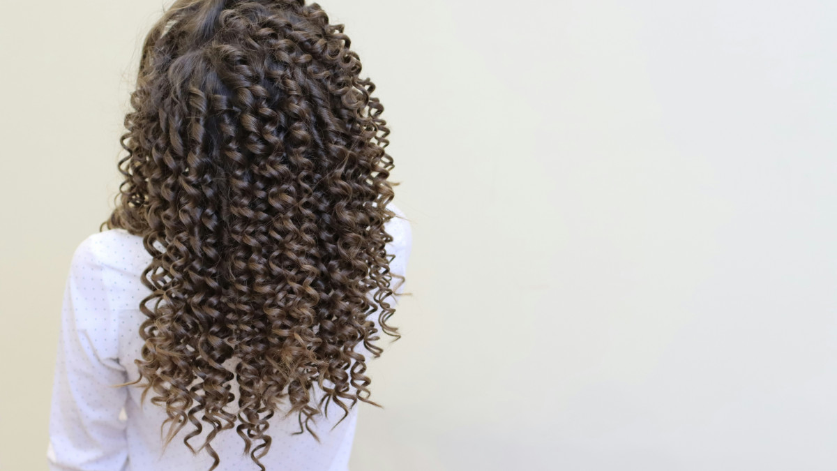 jeune femme avec de beaux cheveux bouclés porte une chemise blanche